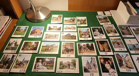 A numbered auction lot of postcards laid out on a felt-covered table under a desk lamp.